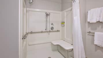A bathroom with a shower, grab bar, bench, and towel rack.