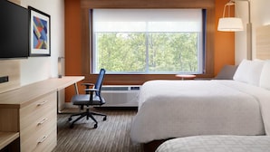 A hotel room with a large bed, a desk with drawers, a chair, a small table, and a window with a view of trees. - Holiday Inn Express & Suites Dayton East - Beavercreek by IHG (Dayton)