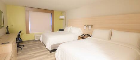 A hotel room with two beds, a desk, and a chair.