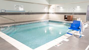 A swimming pool with clear water, marked depth levels, and a lifeguard chair.