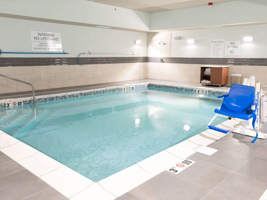 A swimming pool with clear water, marked depth levels, and a lifeguard chair.