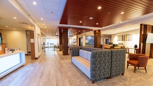 A modern hotel lobby with a reception desk, seating area, and a large wall mural. - Holiday Inn Express & Suites Dayton East - Beavercreek by IHG (Dayton)
