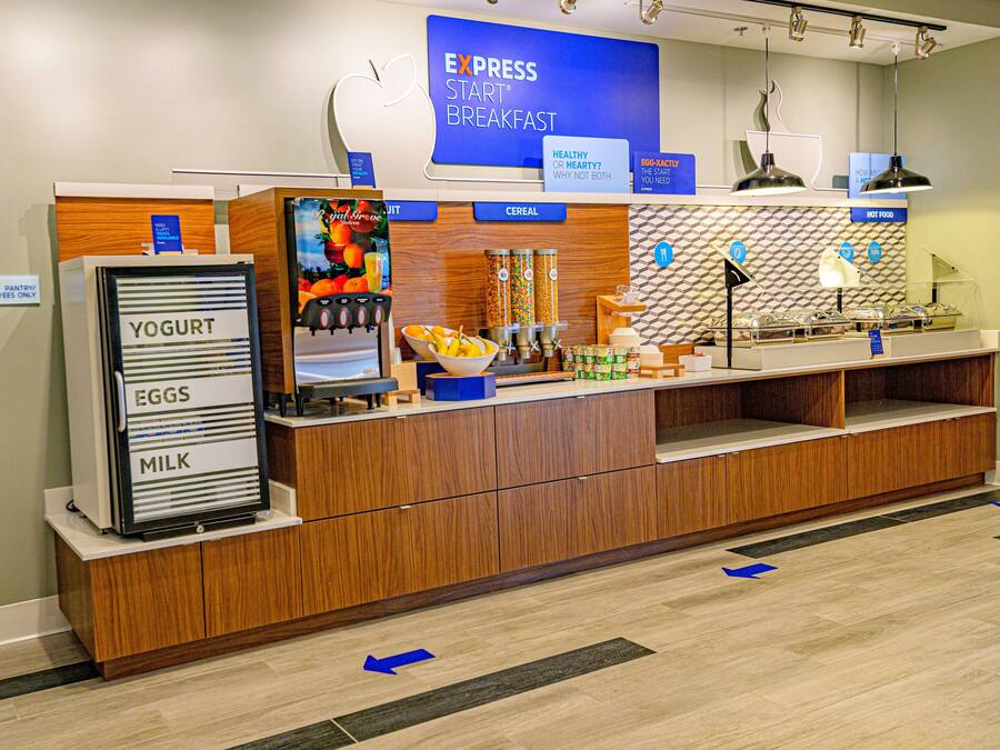 A breakfast counter with a sign for Express Start Breakfast, a yogurt dispenser, and various food items.