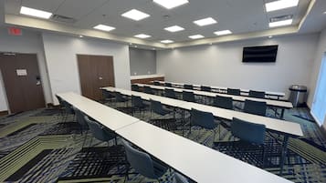 A conference room with long tables and chairs, a door marked "EXIT", and a trash can.