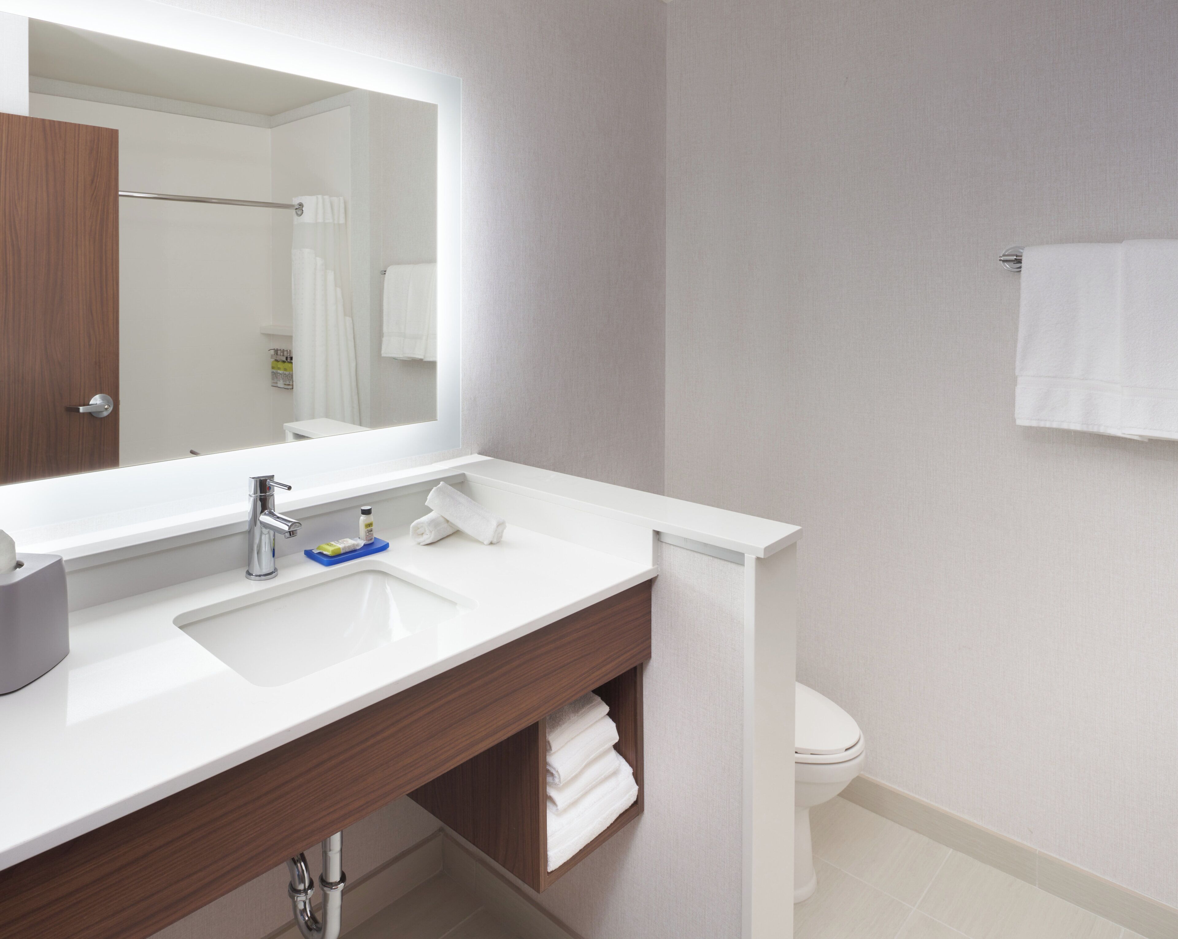 A modern bathroom with a white sink, a mirror, and a toilet.