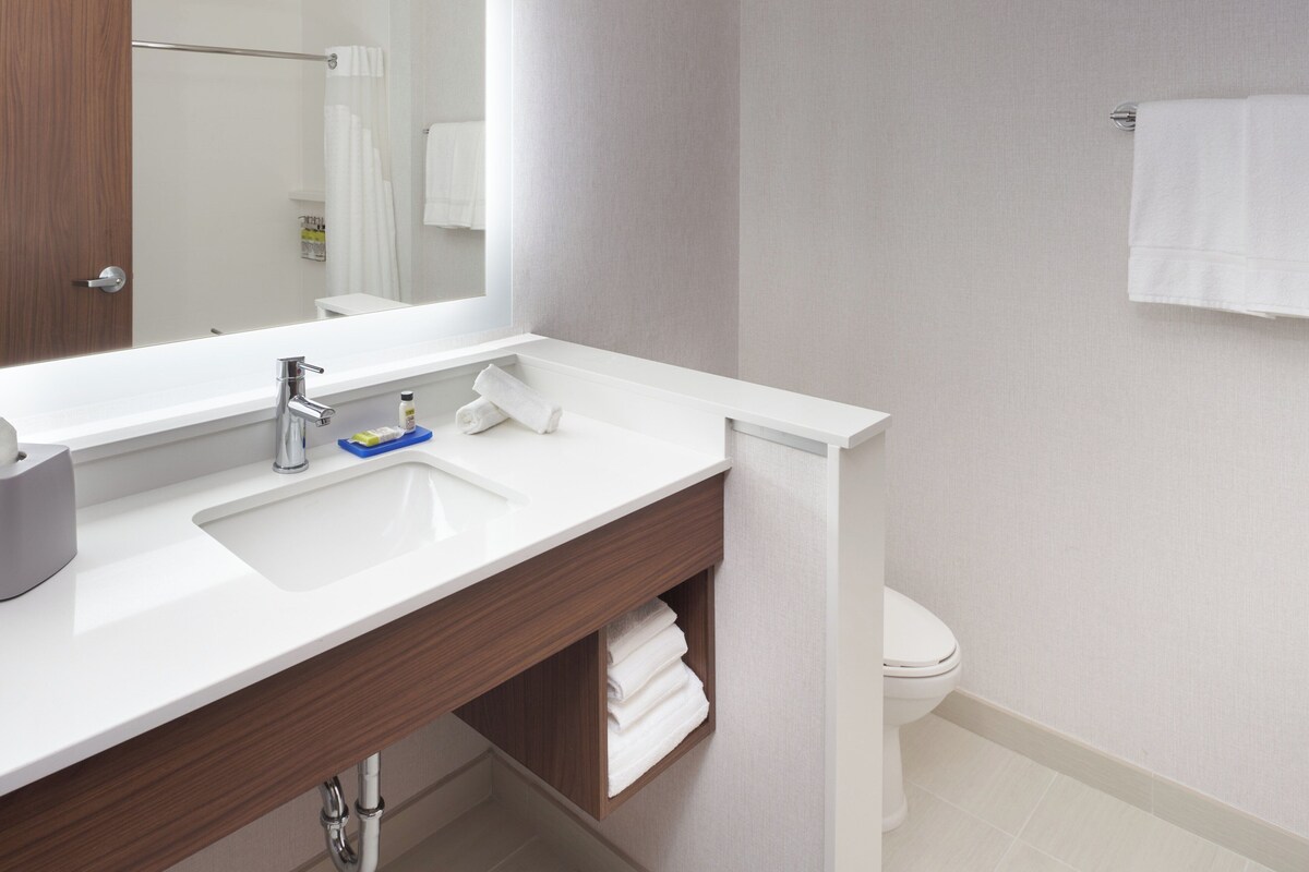 A modern bathroom with a white sink, a mirror, and a toilet.