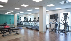 A gym with treadmills, elliptical machines, and weight benches.