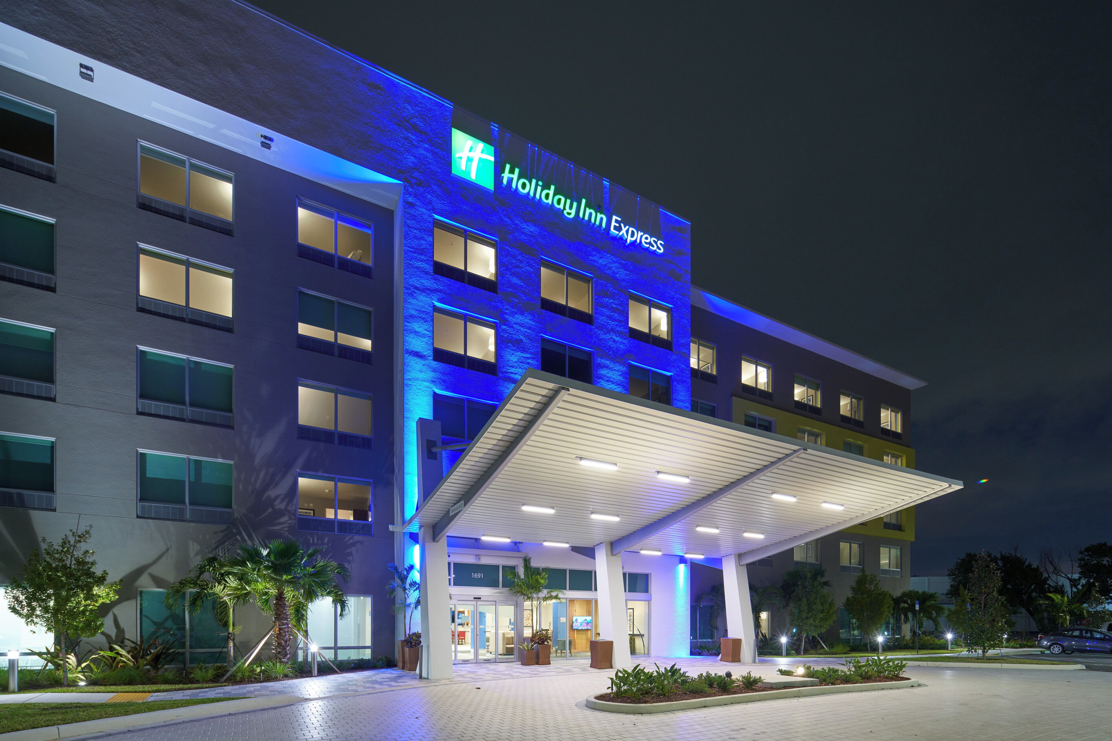 Edificio de Holiday Inn Express con entrada cubierta, múltiples ventanas y fachada bien iluminada.
