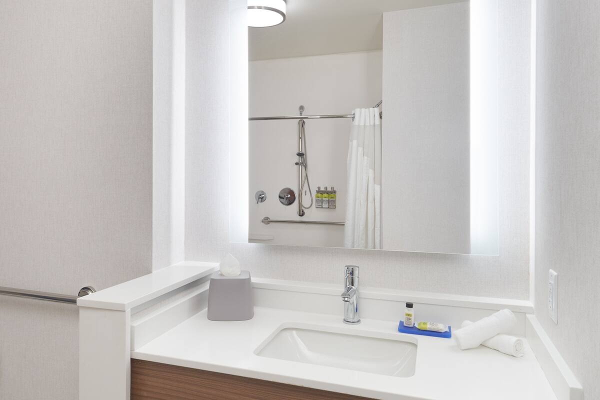 A modern bathroom with a white sink, a mirror, and a shower.