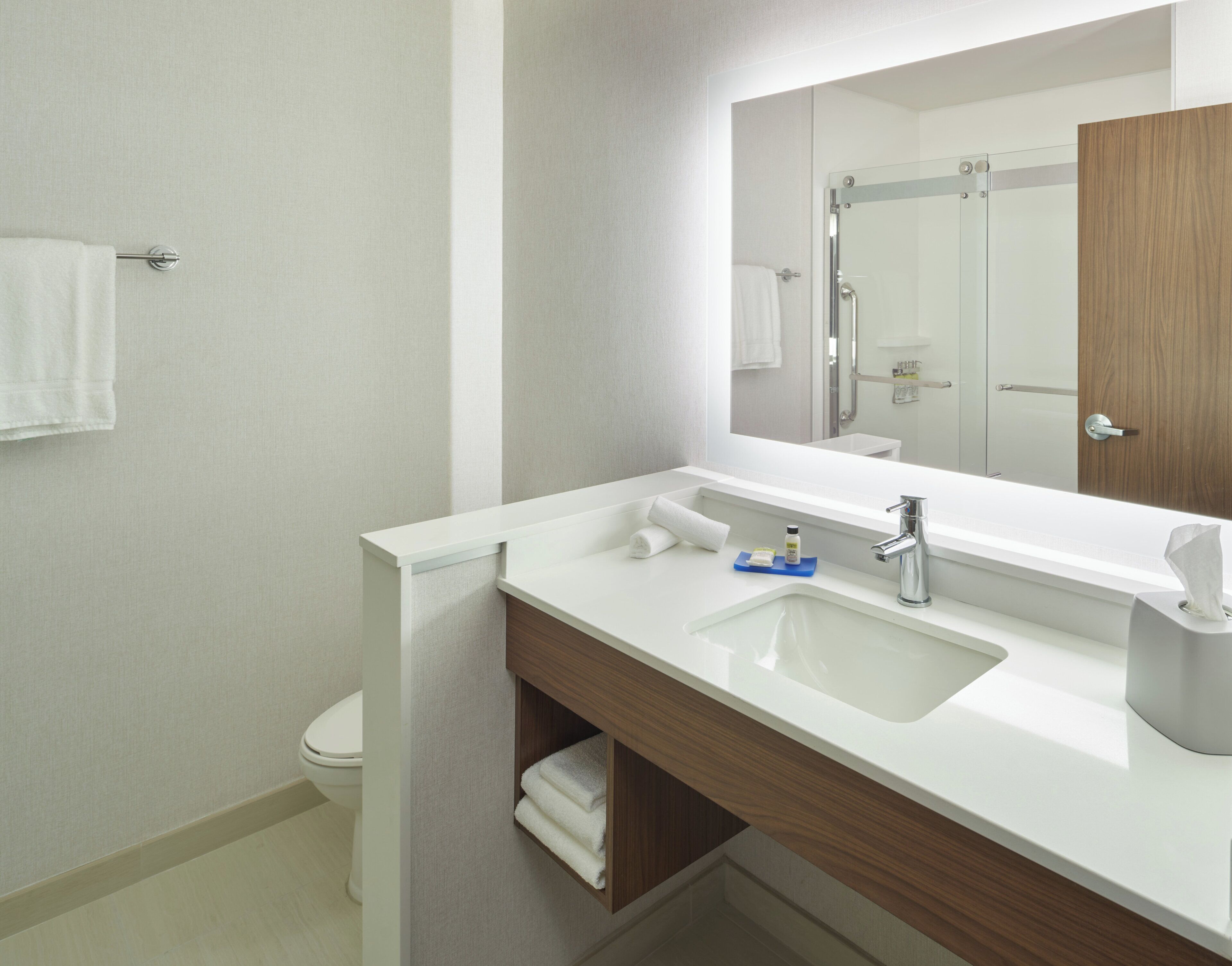 Een moderne badkamer met een witte wastafel, een spiegel en een houten opbergmeubel.