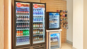 A vending machine area with multiple beverage dispensers, including Coca-Cola and other brands, and a small refrigerator. - Holiday Inn Express Doral Miami by IHG (Miami)