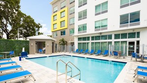 A swimming pool with blue lounge chairs and a small covered area. - Holiday Inn Express Doral Miami by IHG (Miami)