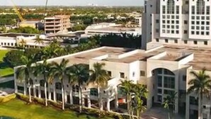 A large hotel with multiple floors, surrounded by palm trees and other buildings. - Holiday Inn Express Doral Miami by IHG (Miami)