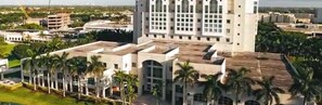 A large hotel with multiple floors, surrounded by palm trees and other buildings. - Holiday Inn Express Doral Miami by IHG (Miami)