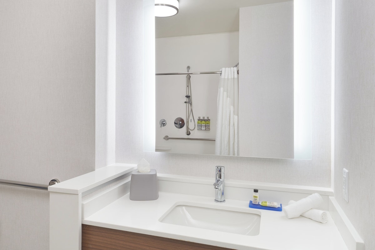 A bathroom with a white sink, a mirror, and a shower area.