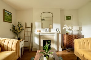 A living room with a fireplace, a mirror, a wooden ladder, and two sofas. - Darly Cottage (Cheltenham)