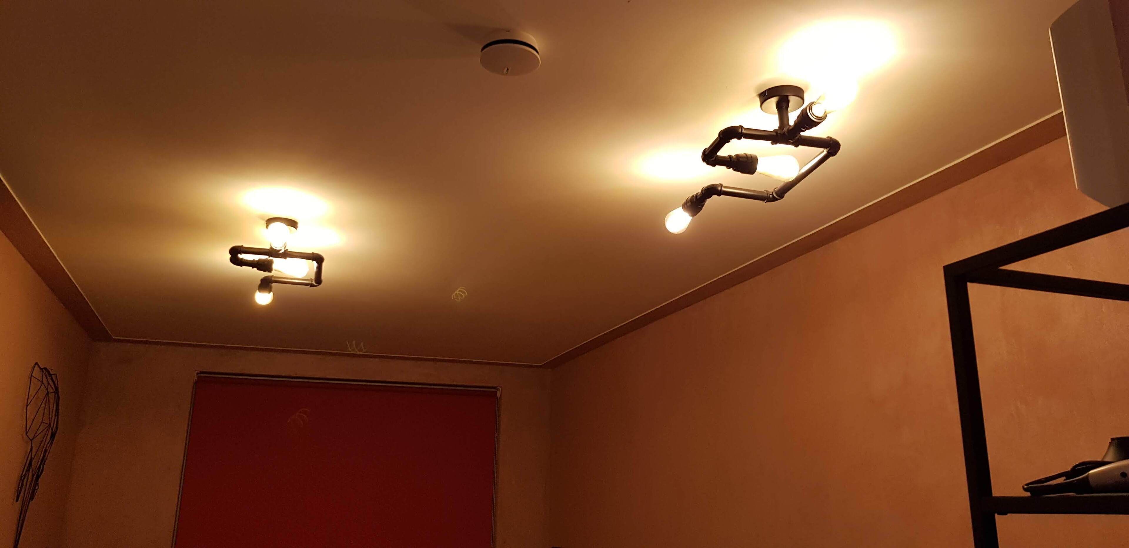 A ceiling with three light fixtures and a red door.