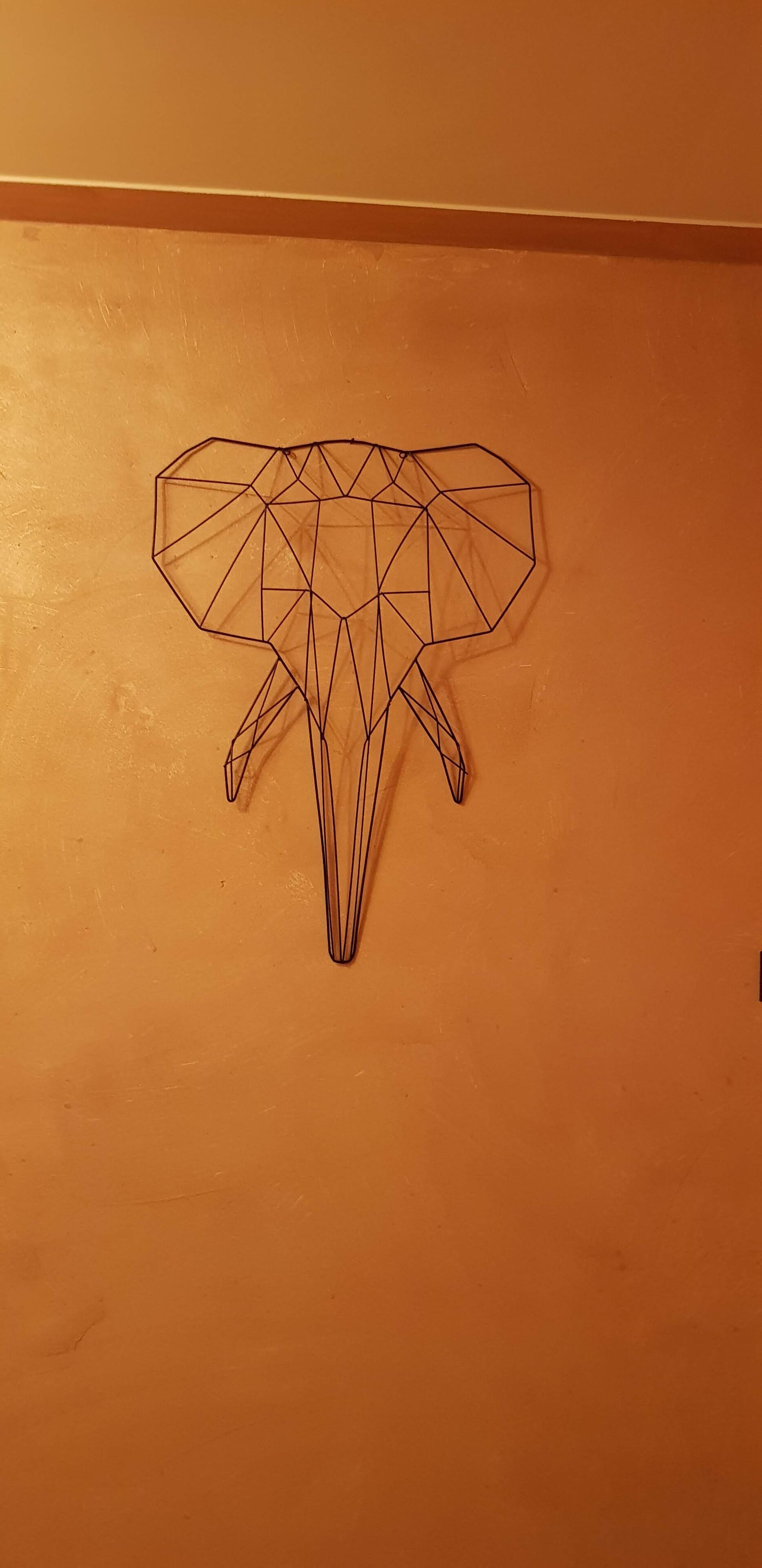 Een geometrisch kunstwerk aan de muur, op een oranje achtergrond.