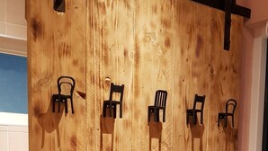 Une porte coulissante en bois munie de plusieurs crochets noirs pour suspendre des chaises.