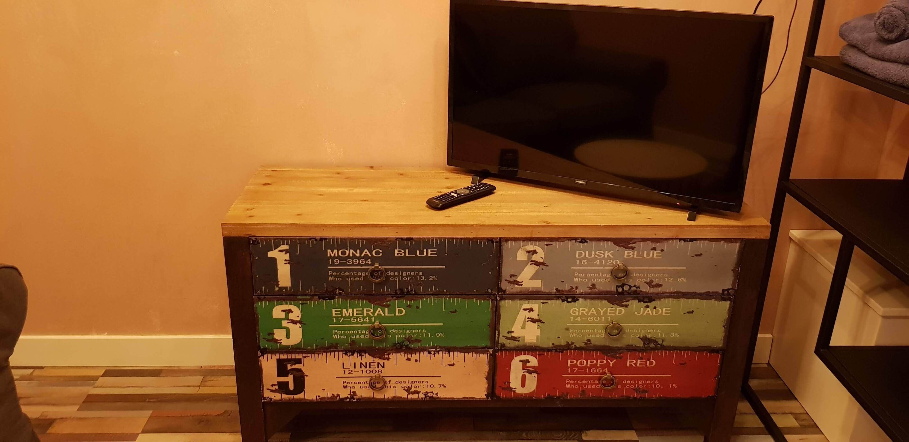 Un meuble en bois pour téléviseur, équipé d’une télécommande et affichant des statistiques sur l’utilisation des couleurs.