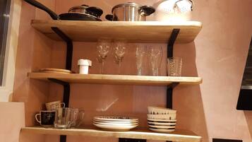 A kitchen shelf with various items including glassware, plates, and a mug.