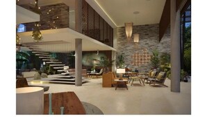 A spacious, modern interior with a central staircase, comfortable seating areas, and a stone accent wall. - LUXURY APARTMENT IN KAAN HA, BAHIA PRINCIPE (Akumal)