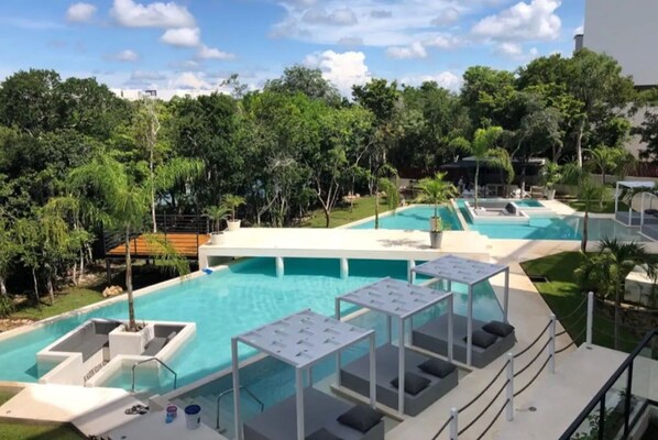 Relax by the central pool surrounded by lush greenery and trees, or unwind in one of the smaller pools.