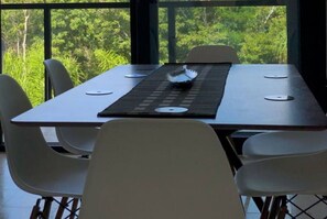 Enjoy meals in a serene setting with a view of lush greenery from the comfort of this dining area.