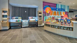 Zona de venta con aperitivos y bebidas, un mostrador con un mural colorido y un suelo de baldosas limpias.