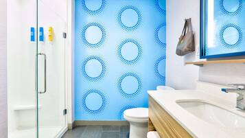 A modern bathroom with a glass shower enclosure, a white toilet, and a sink with a wooden vanity.