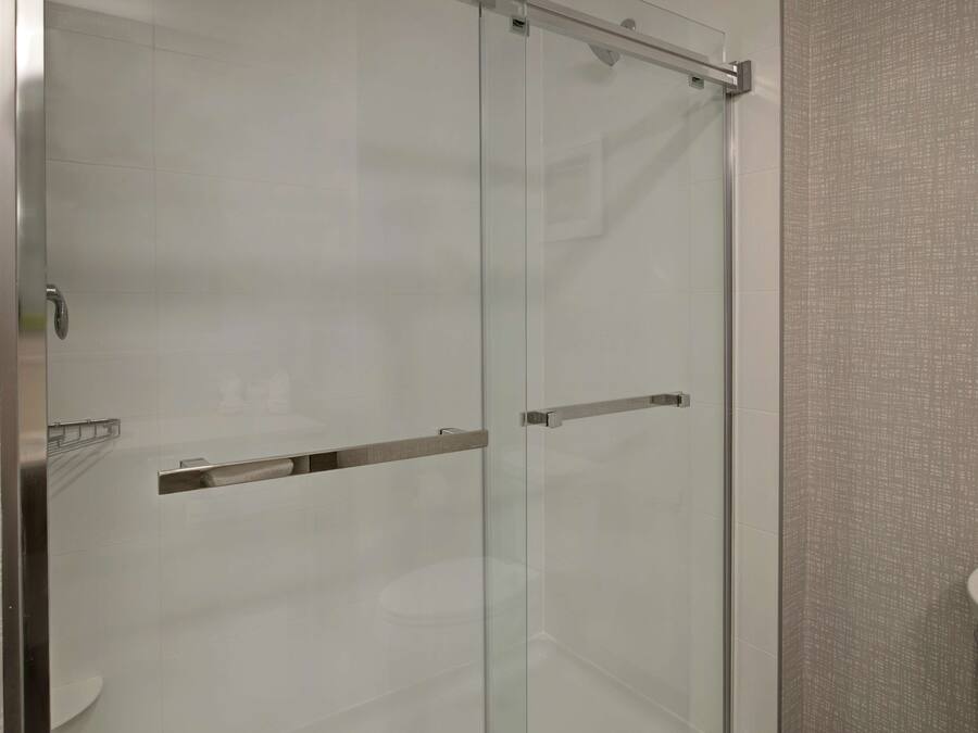 A modern bathroom with a glass shower enclosure, a toilet, and a towel rack.