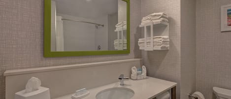Un baño con lavamanos, espejo, toallero, inodoro y caja de pañuelos.