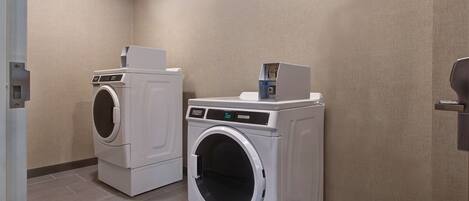 A laundry room with two front-loading washing machines and a dryer.