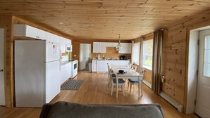 A spacious kitchen with wooden cabinets, a refrigerator, and a dining area with a table and chairs. - Lake Front Cottage Right Across Street ORV And Snowmobile, Blue Bear trail (Mancelona)