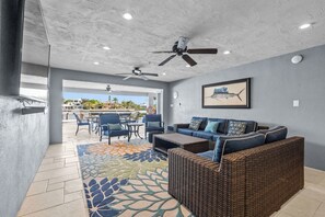 Un vaste patio aménagé avec des meubles en osier, des ventilateurs de plafond et une vue sur l’océan.