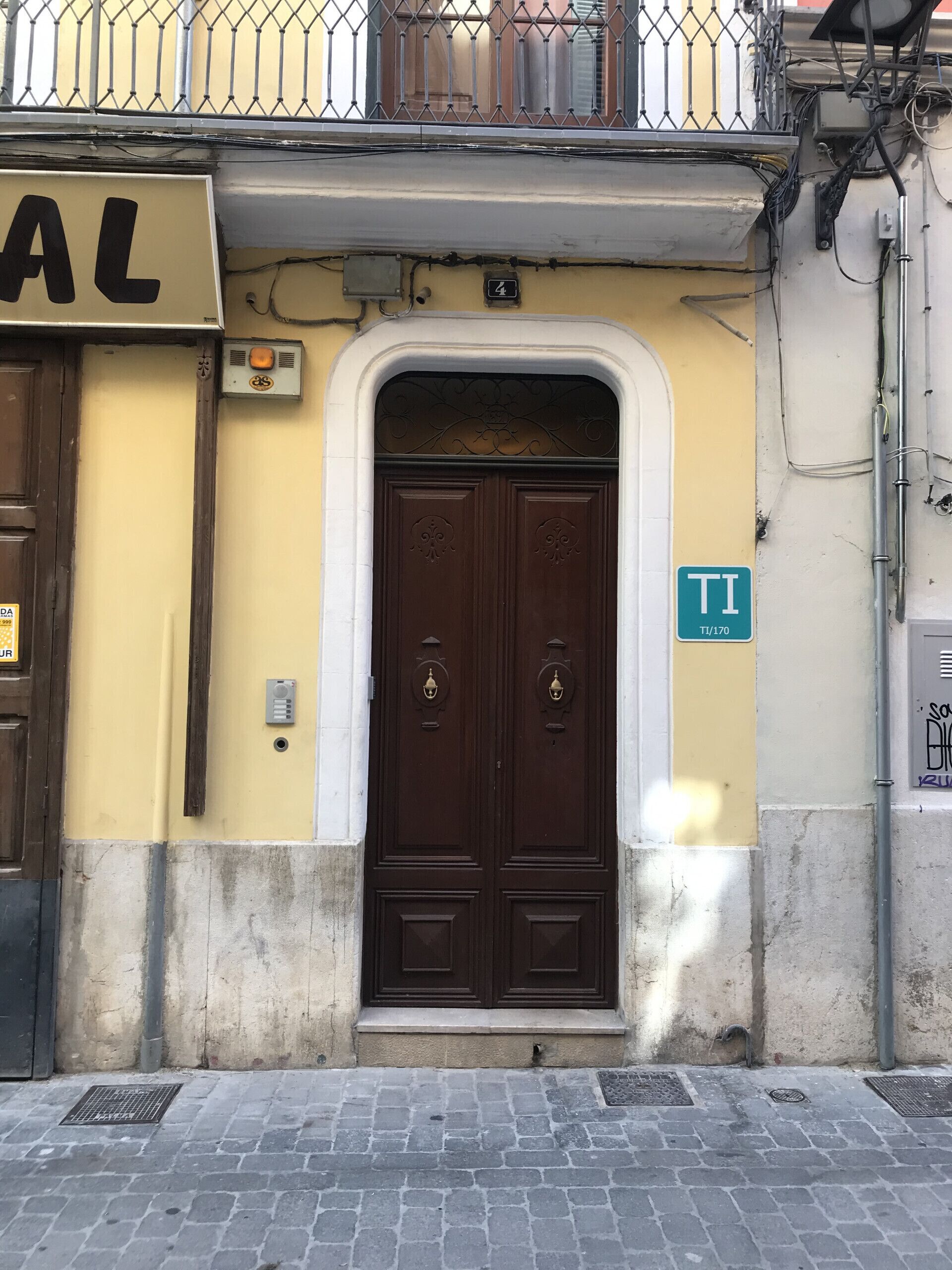 A building with a double wooden door, a yellow wall, and a sign indicating room number 170.