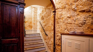 Una escalera de paredes de piedra con una puerta de madera y barandilla de metal.