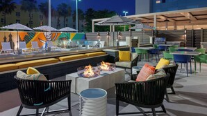 An outdoor seating area with fire pits, umbrellas, and modern furniture. - Hyatt House Tampa Airport Westshore (Tampa)