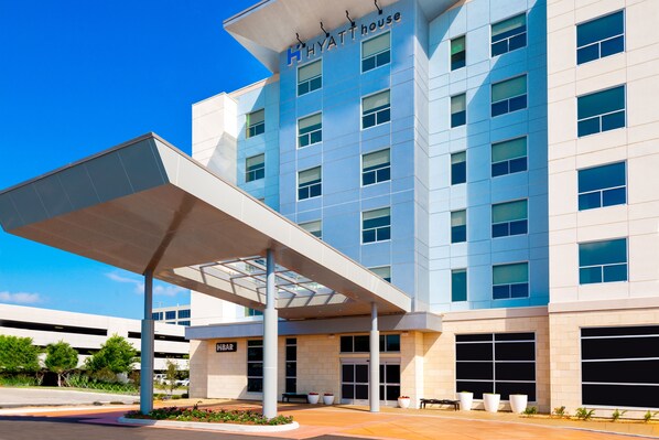 A modern hotel with a covered entrance, large windows, and a sign reading "HYATT HOUSE".
