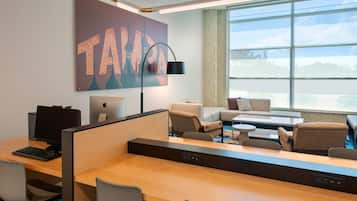 A modern office space with cubicles, a large window with a view, and a prominent artwork on the wall.