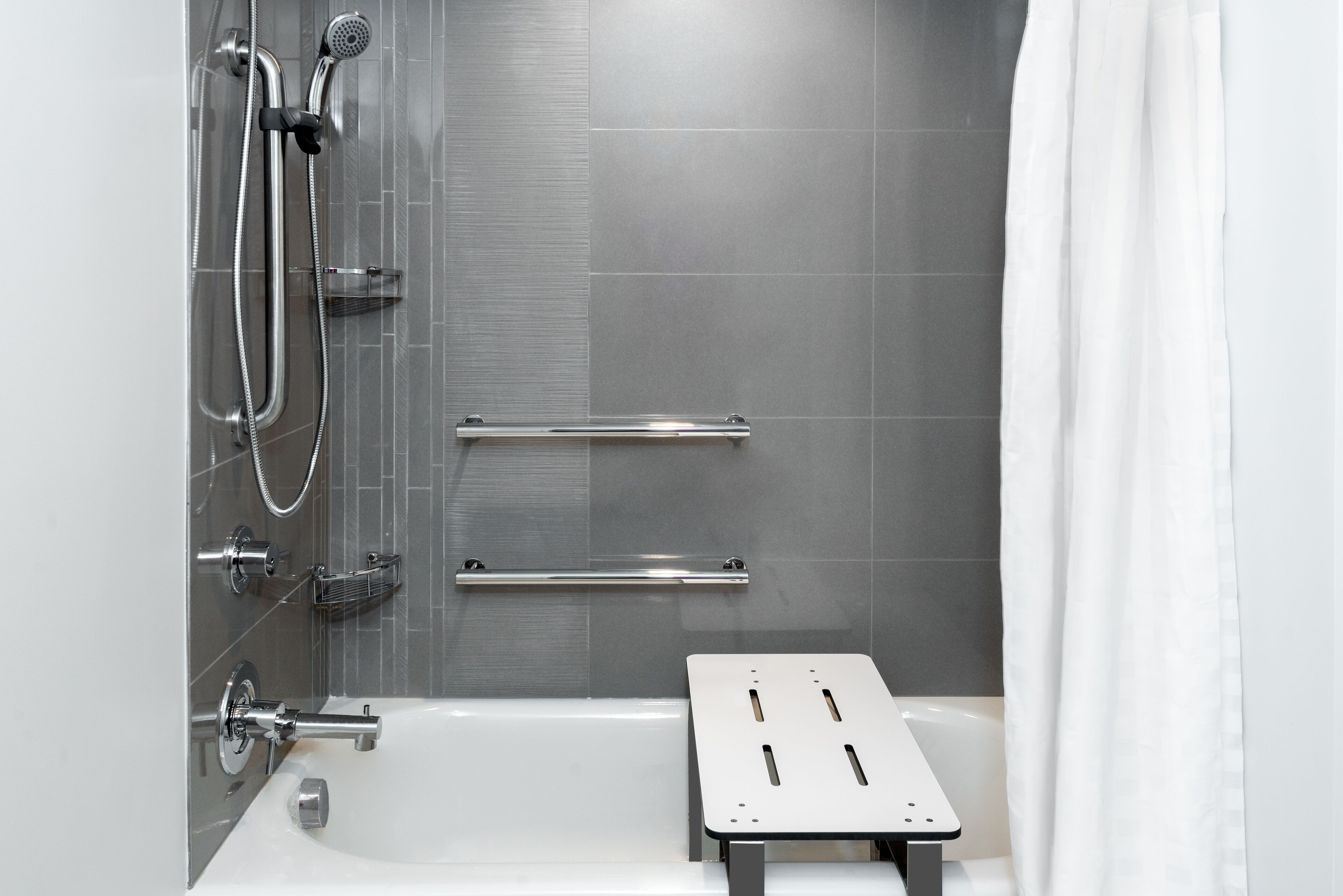 A modern shower area with a glass enclosure, chrome fixtures, and a white shower curtain.
