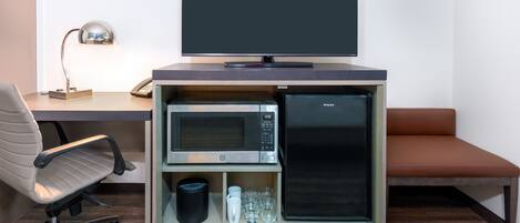 A compact kitchenette with a microwave, refrigerator, and a flat-screen TV.