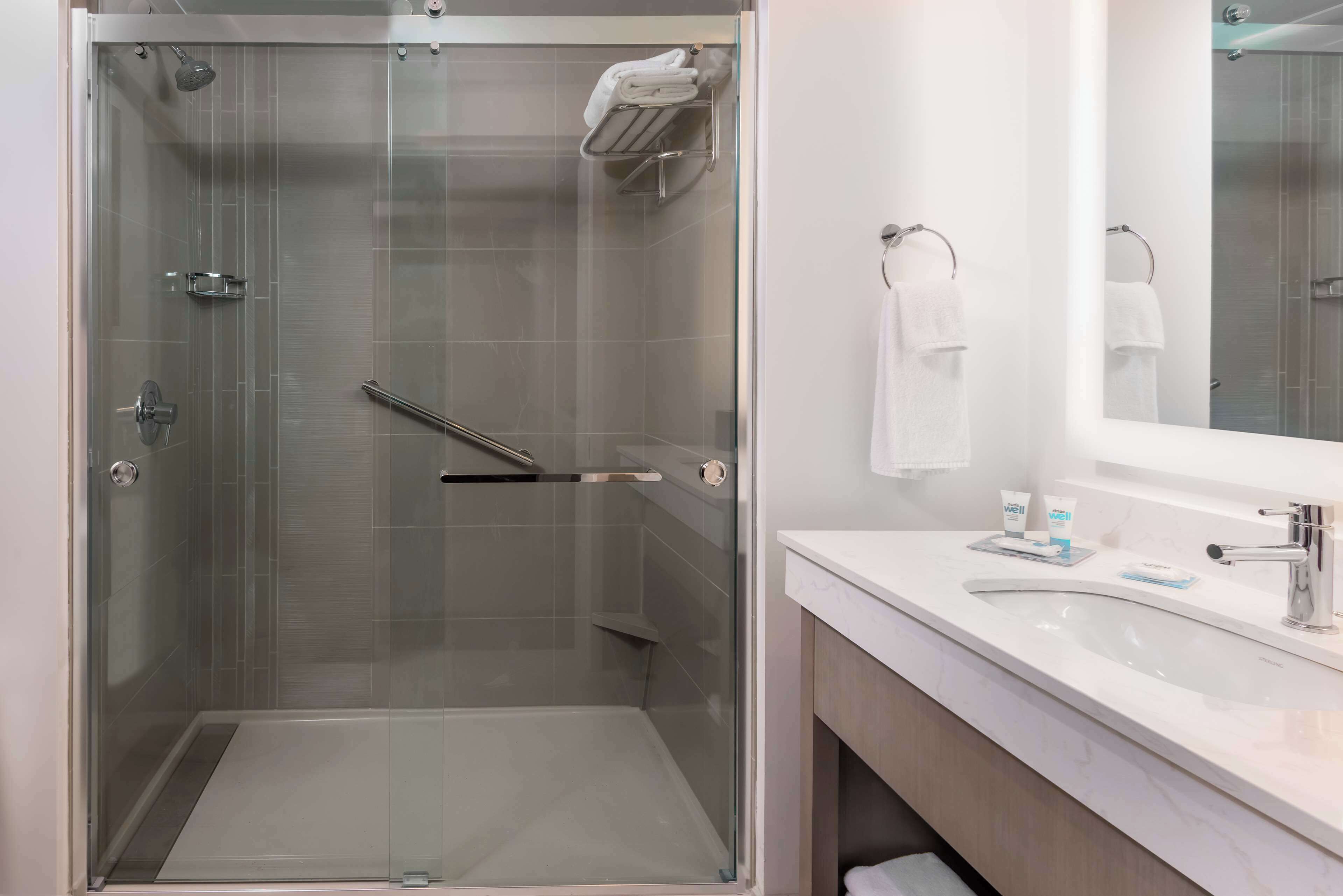 A modern bathroom with a glass-enclosed shower, a white sink, and a mirror.