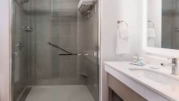 A modern bathroom with a glass-enclosed shower, a white sink, and a mirror.