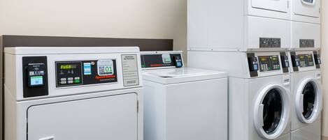 A laundry facility with multiple washing machines and dryers, including a commercial dryer.