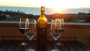 A bottle of wine and three glasses on a table with a view of the ocean and a sunset. - Panoramic Ocean View-No Stairs-King Bed-Walkin shower, 24hr Manned Sec. Gates (Dana Point)
