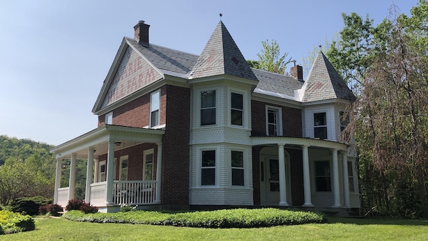 A large, two-story house with a wrap-around porch and multiple chimneys. - Historic Vermont Farmhouse on 12 Acres, Quaint Vermont Experience. (Andover)
