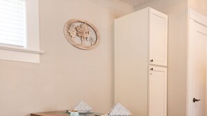 Een kamer met een houten tafel, twee stoelen, een witte deur en een decoratie aan de muur.