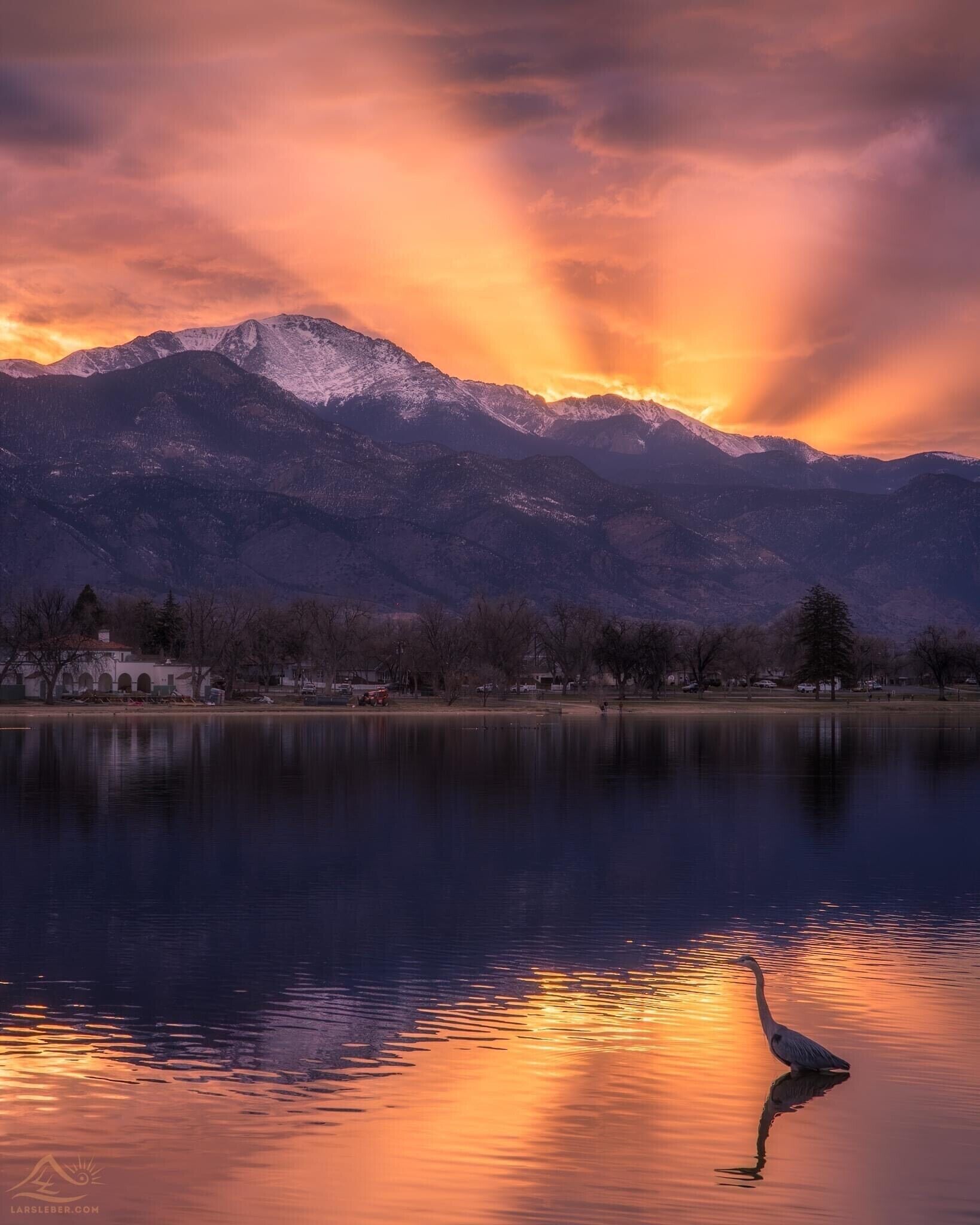 A serene lake with mountains in the background and a building with arched windows near the water's edge.