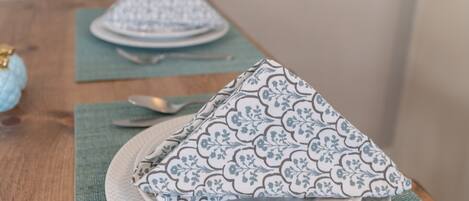 A dining table with a placemat, a folded napkin, a spoon, and a fork.
